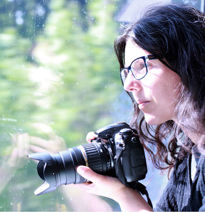 Jennifer Scales, holding a camera, looking out of a train window