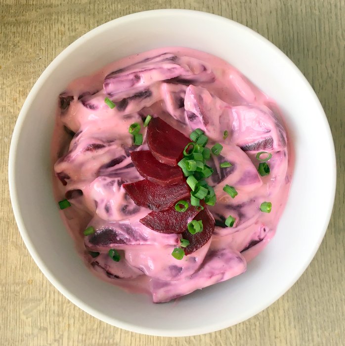 A bowl of beetroot salad, decorated with chives. 