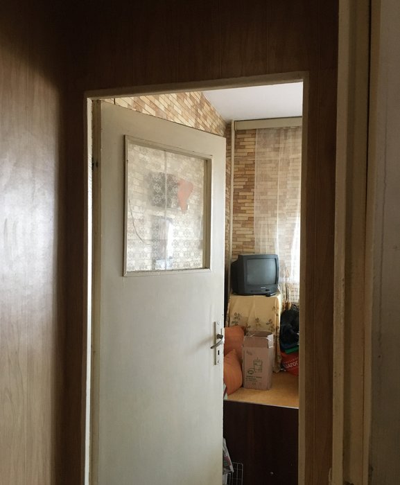 Blick durch eine offe Tür un ein vollgesteltes Zimmer. Ein kleiner alter Röhrenfernseher ist zu erkennen.