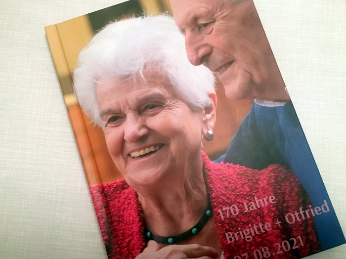 A photo book on a table. The cover shows two smiling people. The text is "170 years of Brigitte and Otfried".