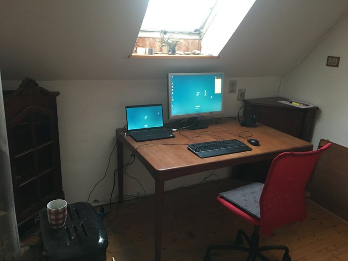 A desk with laptop, keyboard and monitor