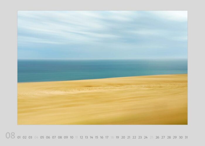 Kalenderblatt 08 aus dem Kalender "Travelscapes 2024" von Jennifer Scales. Das Motiv ist eine dynamische Fotografie mit Bewegungseffekten von einer schottischen Küste. Im Vordergrund ist ein weizenfarbenes Feld, im Hintergrund die tiefblaue See mit woligem Himmel